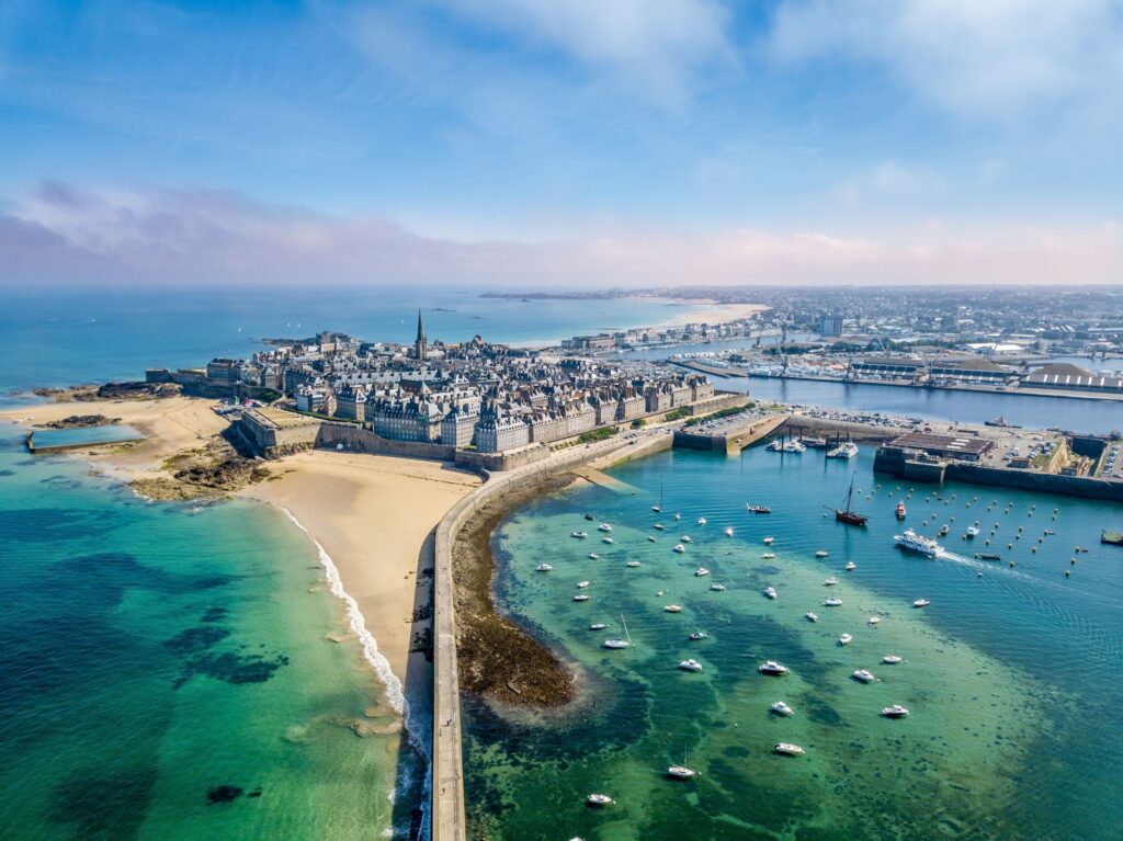Luftfoto af Saint-Malo i Bretagne med bymur, strande og turkisblåt hav fuld af både