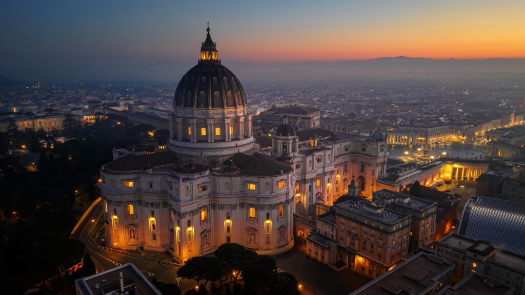 Peterskirken i Rom oplyst i skumringen med udsigt over byens tage og gader